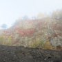 Herbstliche Steinbruchwände im Nebelfeld, vorne bituminöser Schieferstein